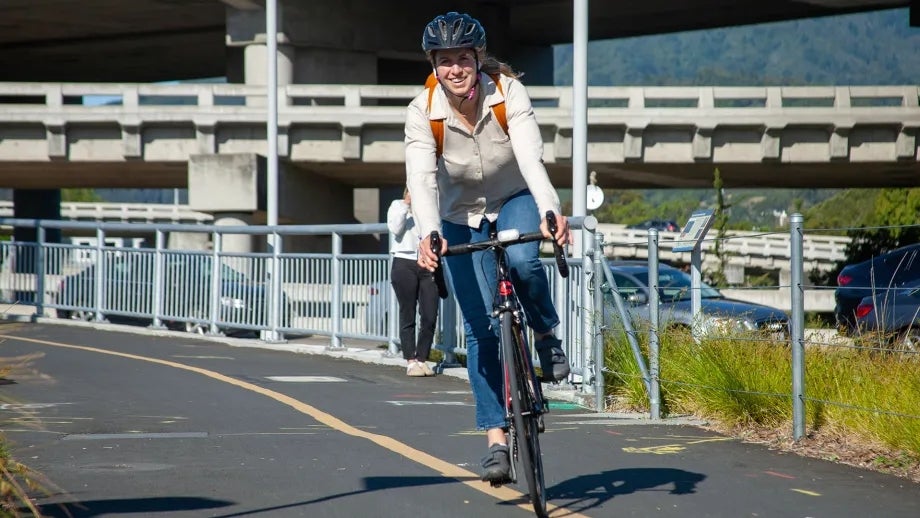 A smiling cylist rides in a protected bike lane.