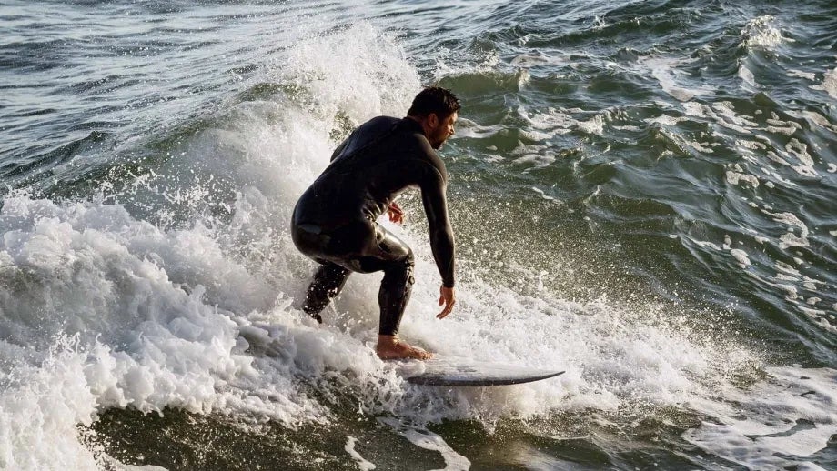 A surfer in a wetsuit catching waves.