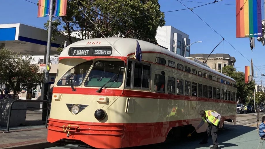 An "F" historic Muni streetcar with Pride flags in the background in the Castro in San Francisco.