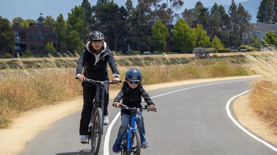 A family biking on a paved Bay Trail path in San Mateo County.