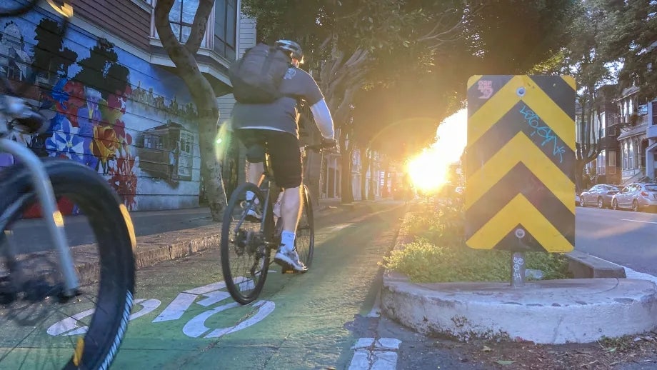 Cyclists riding in a separated bike lane at dusk in San Francisco.