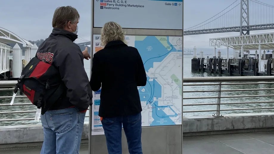 Travelers looking at a ferry system map at the San Francisco Ferry Building.