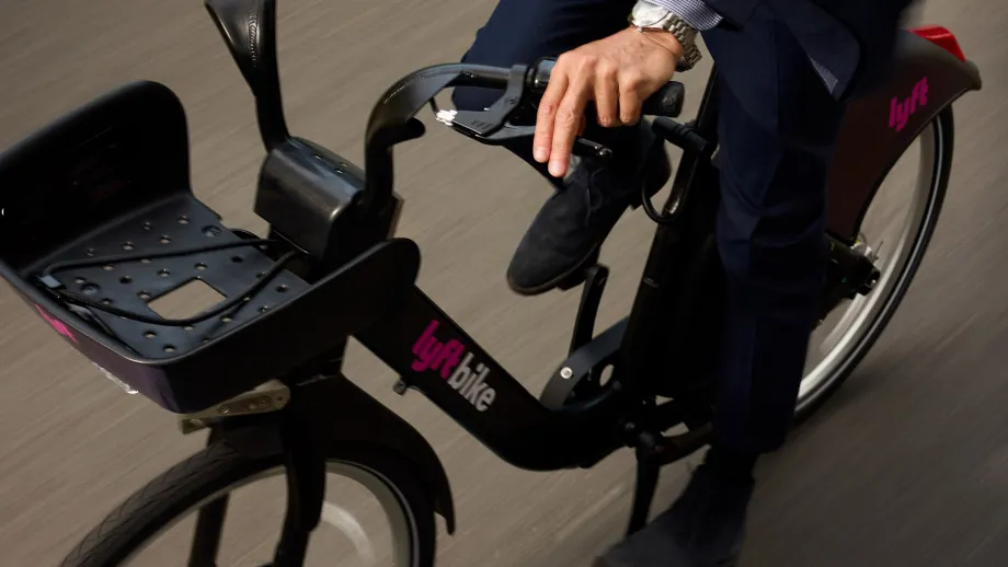 A person in a suit riding a classic, non-electric Lyft Bike.