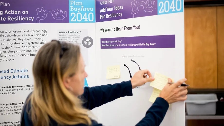 A woman posts a comment note to the resiliency display board at the Plan Bay Area 2040 open house in Napa.