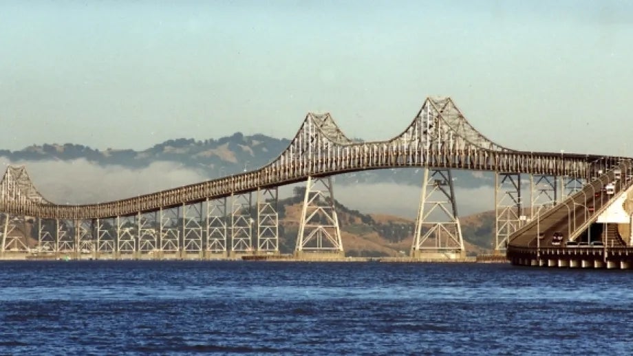 Richmond-San Rafael Bridge with fog in the background and sapphire-blue water below.