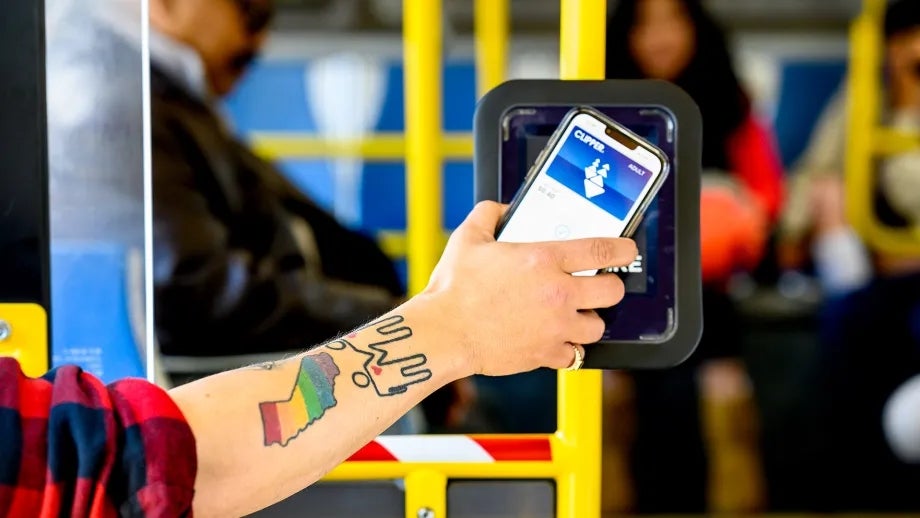 A man with a rainbow California tattoo uses Clipper mobile to pay for transit on Muni.