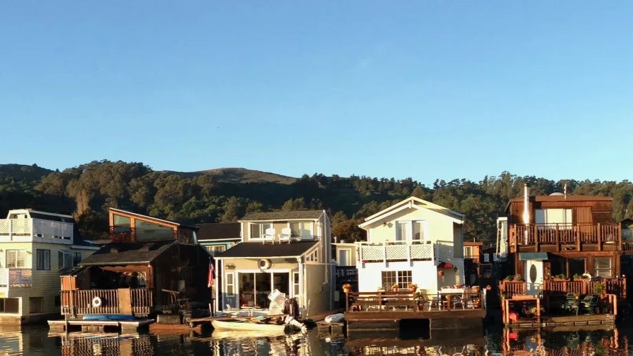 Houseboats in Sausalito reflected in the water on a sunny day.