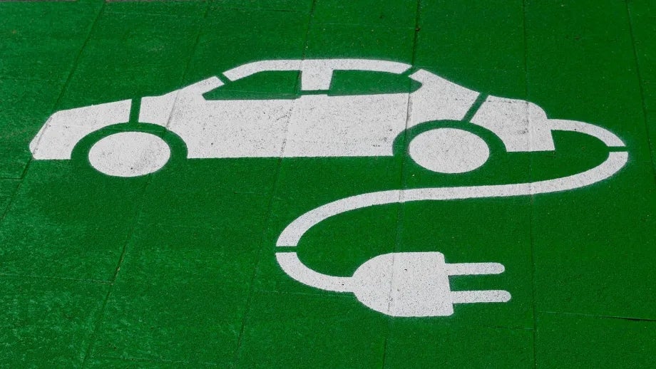 A painted stencil of a sedan with an electric plug coming off the back.