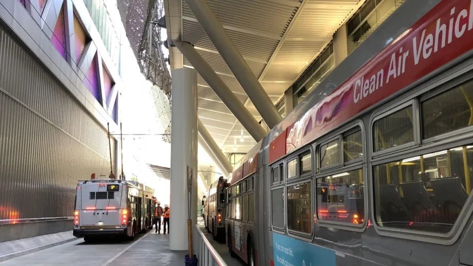 The multi-lane outdoor bus plaza is tucked under the Transit Center's dramatic superstructure.